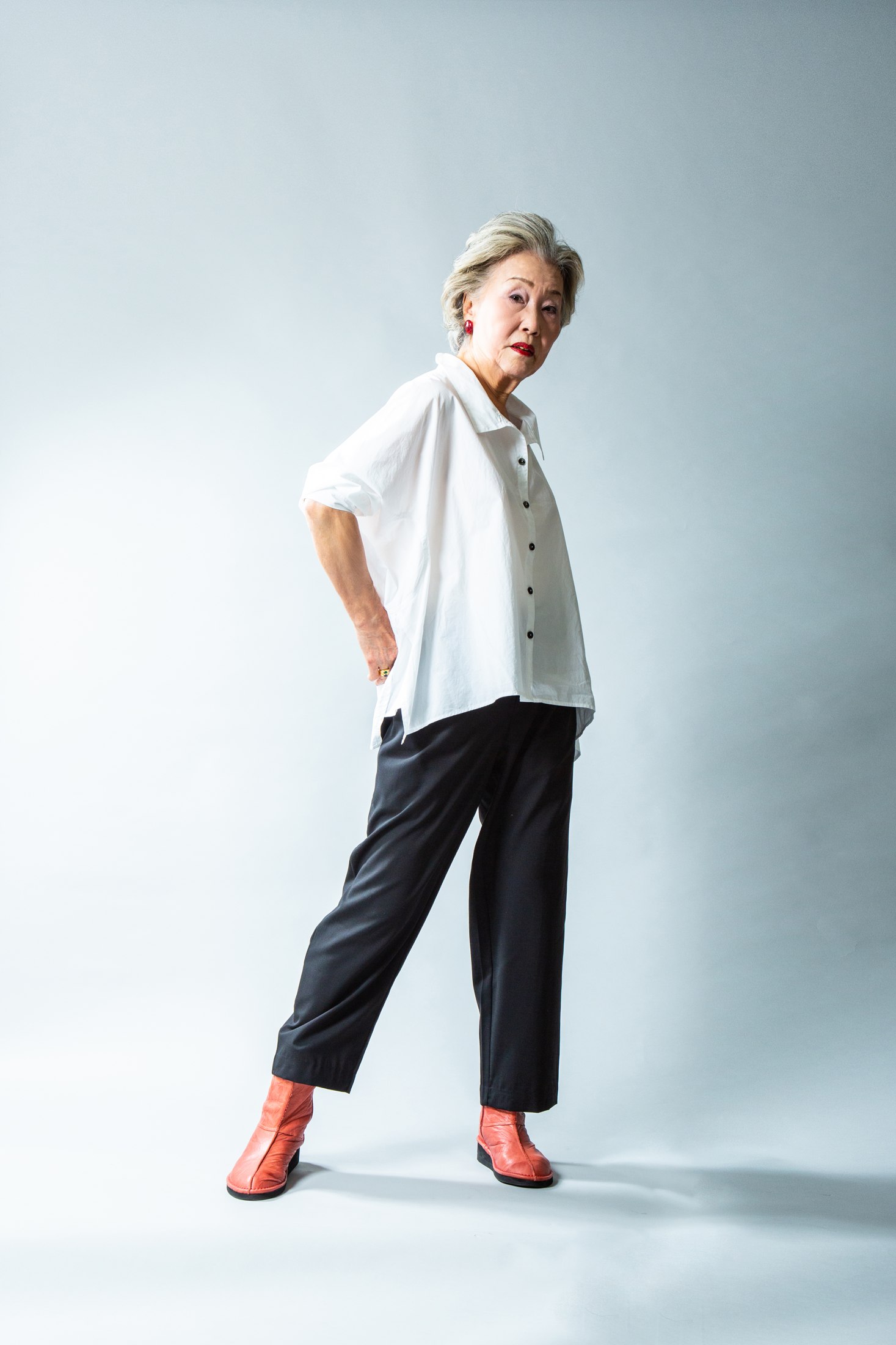 白いシャツと赤いブーツを合わせて立つ女性
