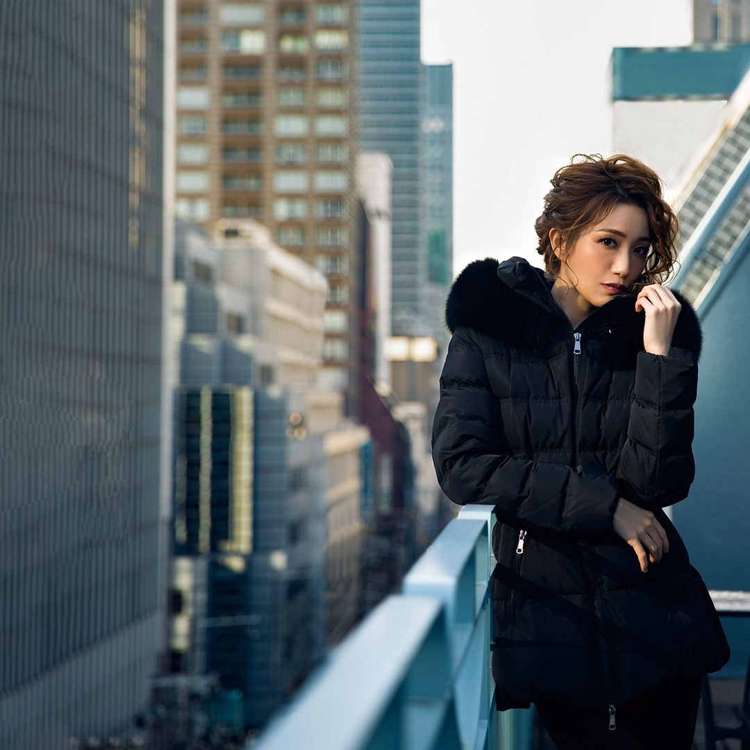 街の建物を背景に黒い衣装を着た女性
