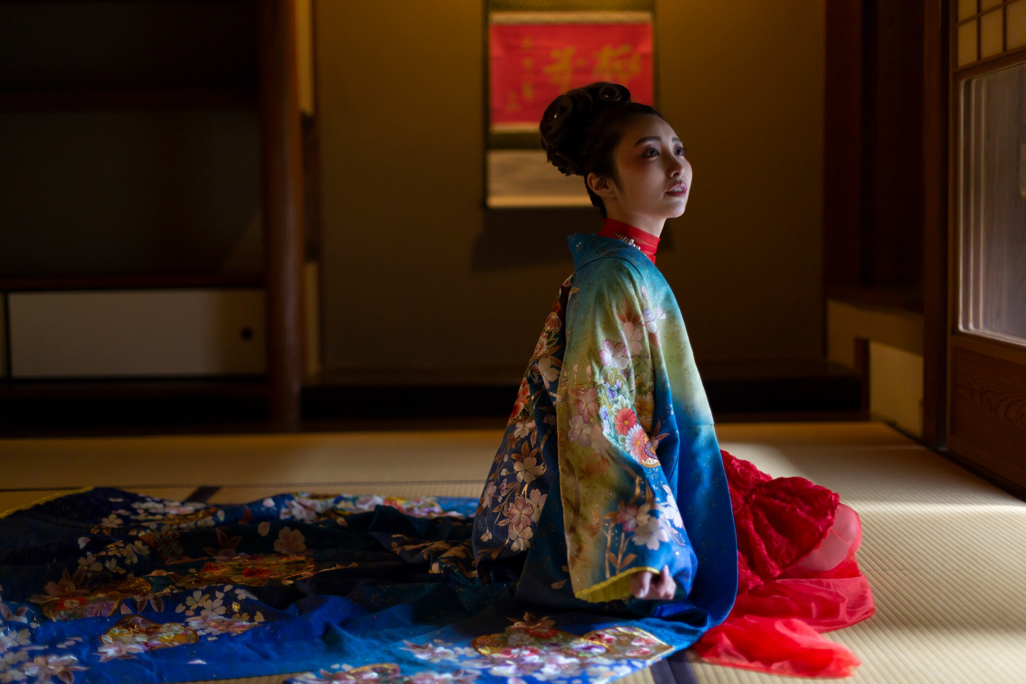 室内の光を受け、鮮やかな着物を広げて座る女性