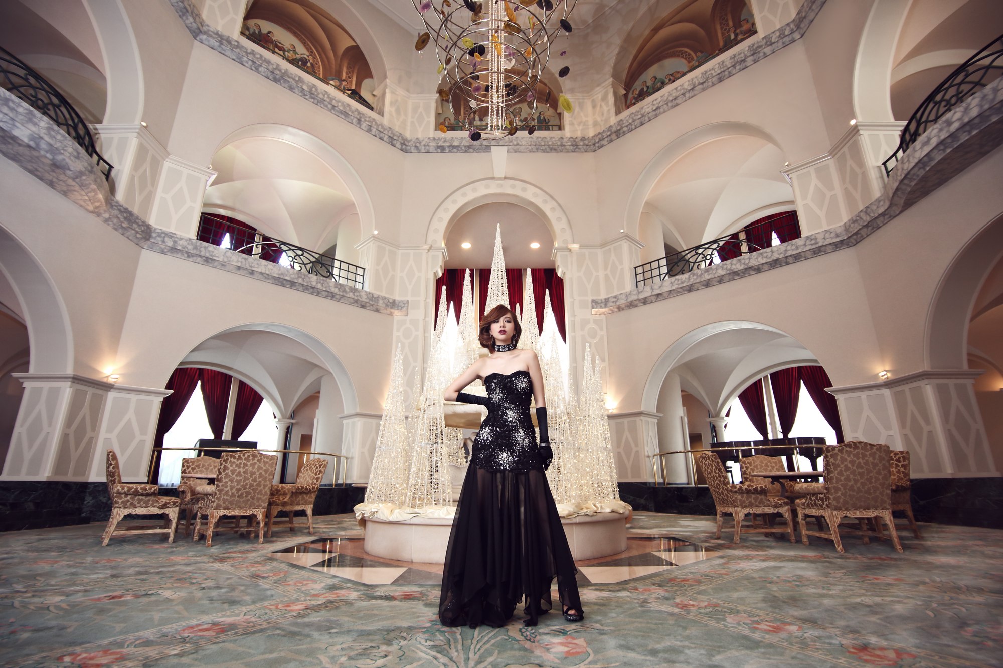 大きなシャンデリアのあるホールに立つ黒いドレスの女性